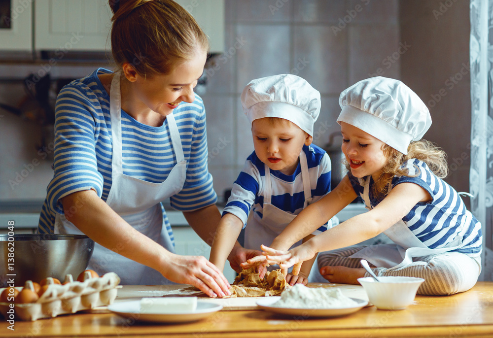 happy family in kitchen. mother and children preparing dough, bake cookies