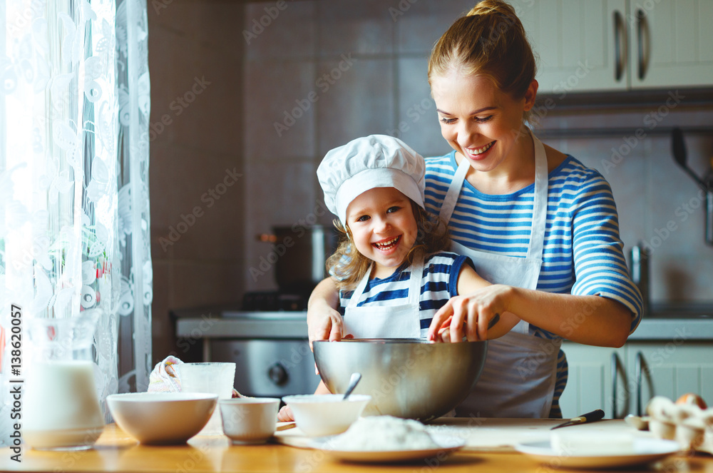 happy family in kitchen. mother and child preparing dough, bake cookies