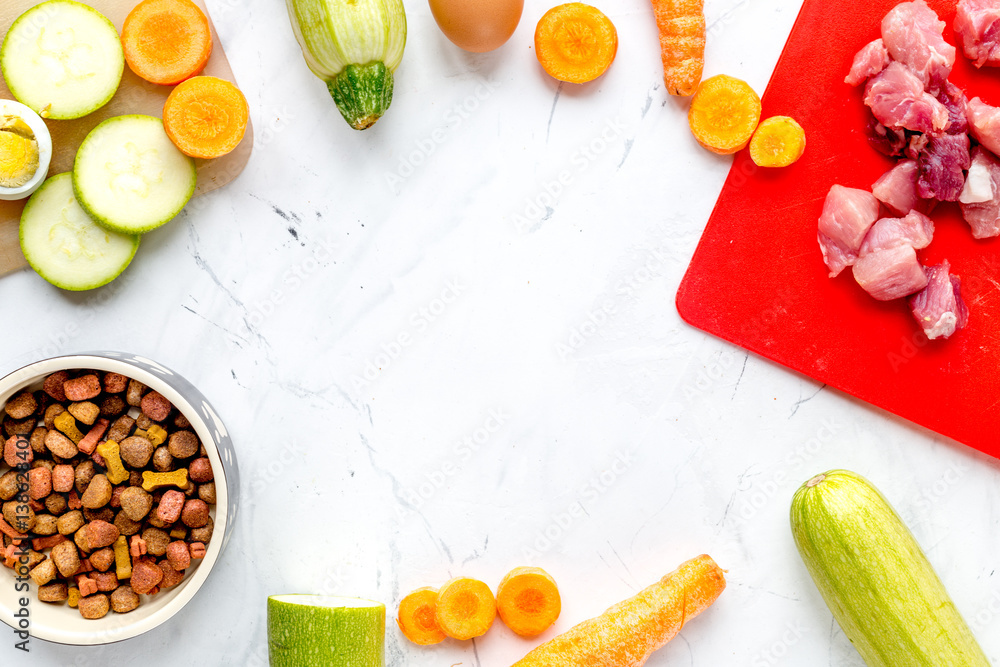 Bowl of dry dogfood, carrot, courgette, meat table background top view mock-up