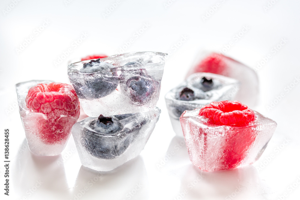 Ice cubes with frozen berries on white background