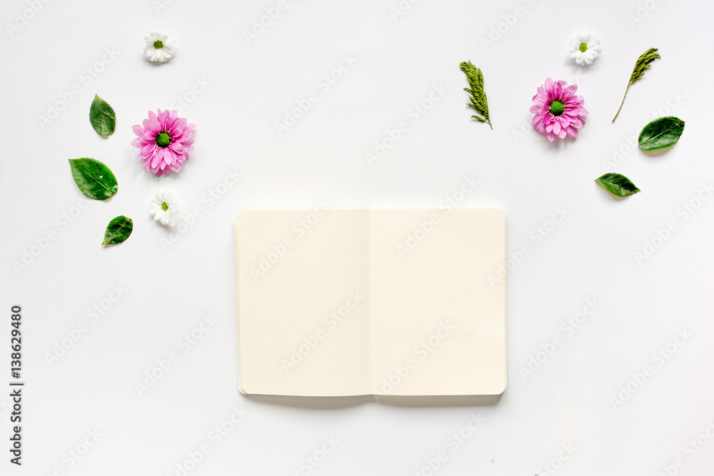 Flower petals and white notebook on table background top view mock-up