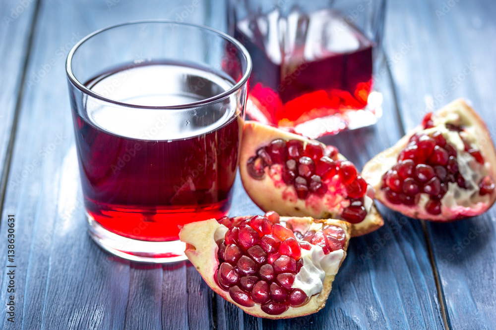 ripe pomergranate and bottle of red juice on wooden background