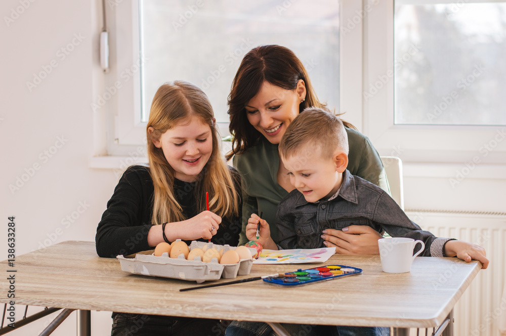 Mother painting with kids at home, having a fun time