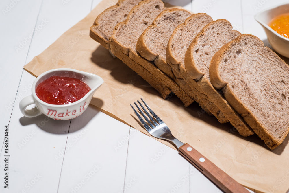 Toast with strawberry and orange jam on a plate on table.