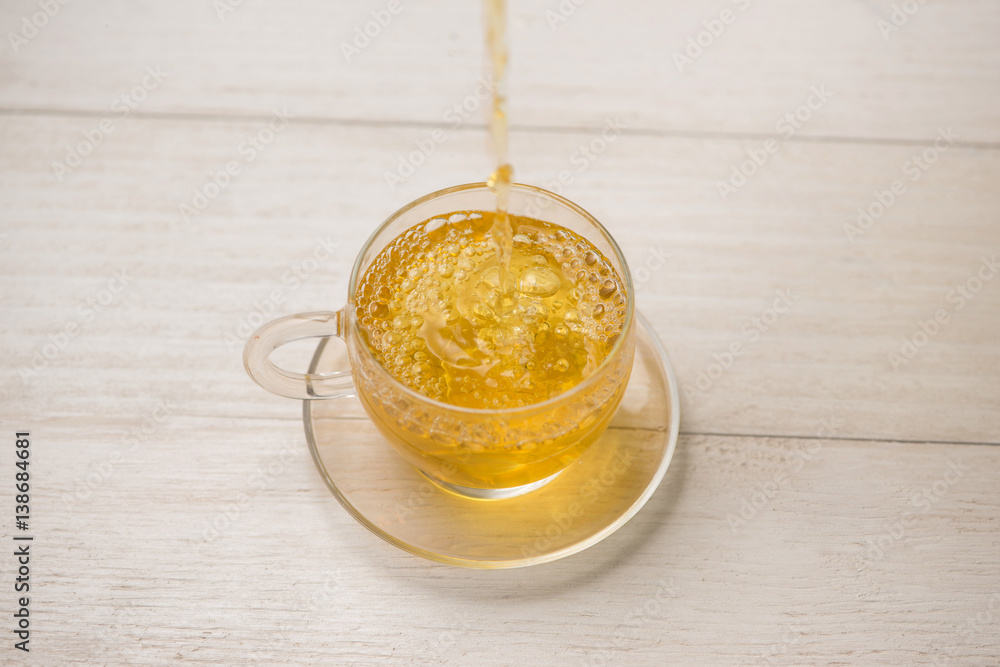 Pouring tea. Cup of hot tea and tea leaf on the wooden table