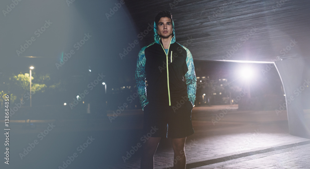 Young sportsman standing on the street at night