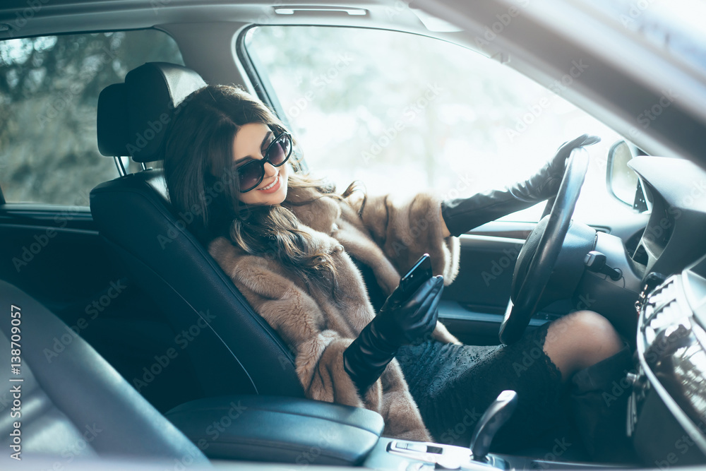 Young beautiful brunette inside the car with wheel in hands