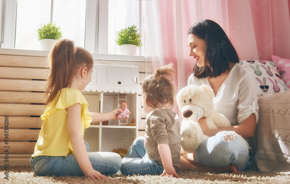 mother and daughters play with doll house