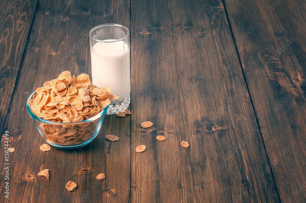 Tasty corn flakes in bowl with glass of milk