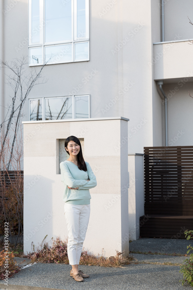 attractive asian woman standing front of modern house