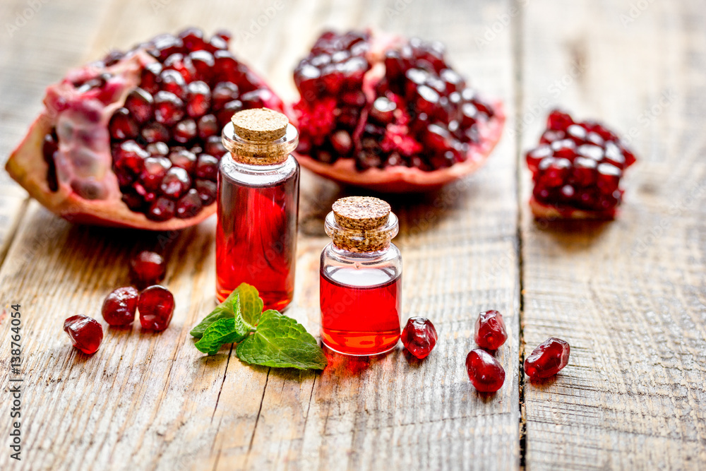 sliced pomegranate and extract in glass on wooden background