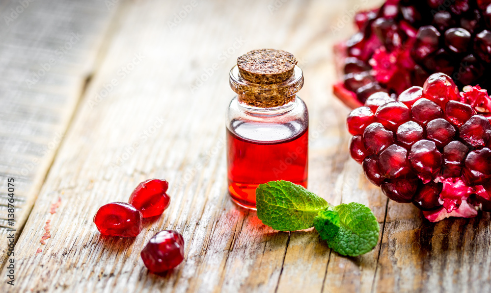 sliced pomegranate and extract in glass on wooden background