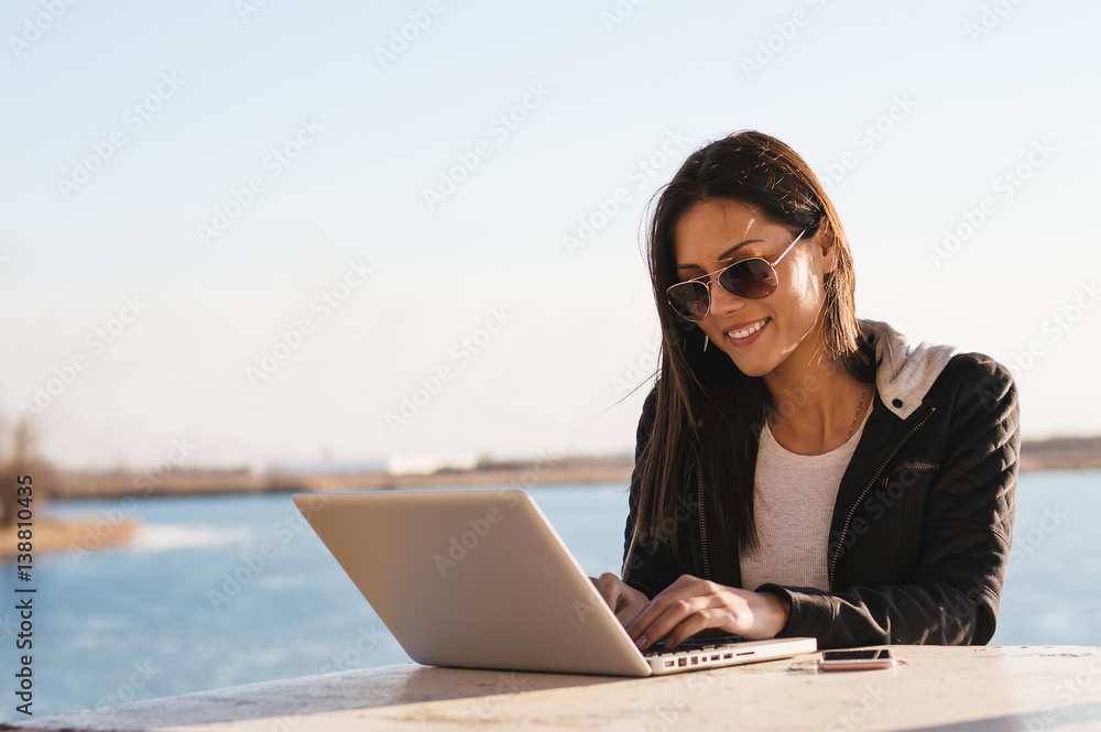 Pretty student girl doing projects on computer on a sunny day outdoor