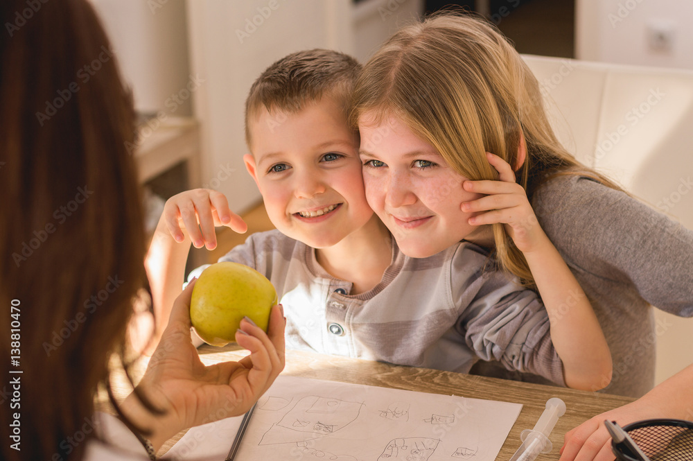 Family time at home. Mother giving apple to kids