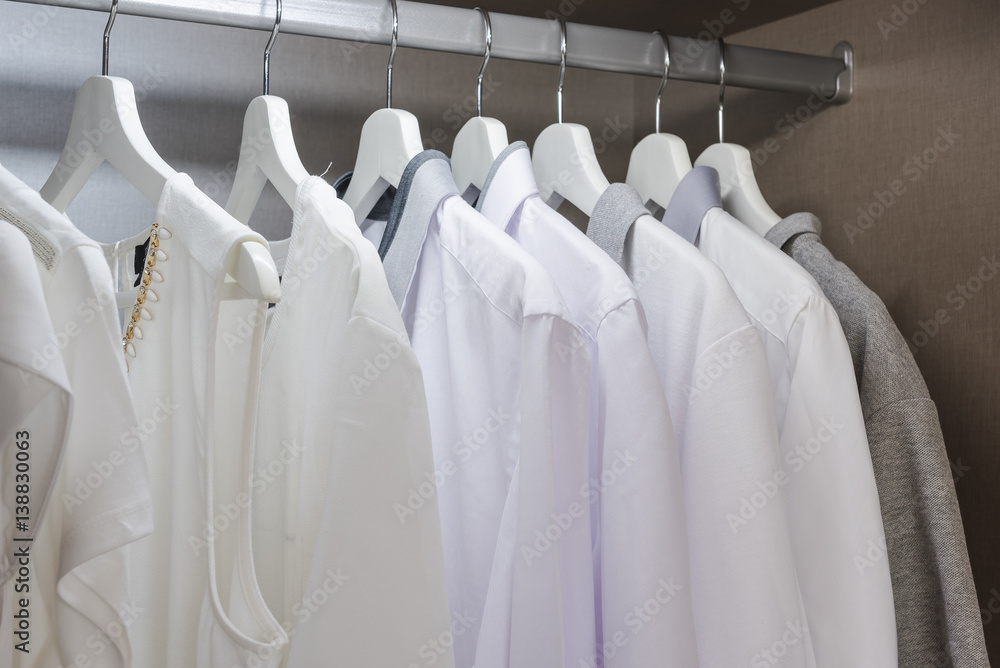 white shirts hanging on rail in wooden wardrobe