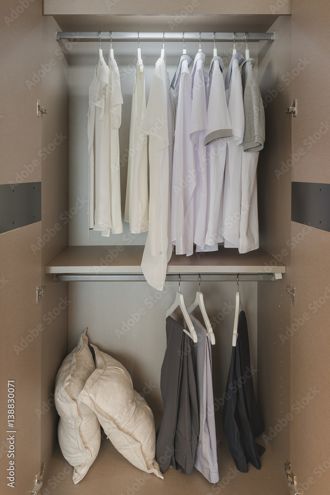 white shirts hanging on rail in wooden wardrobe