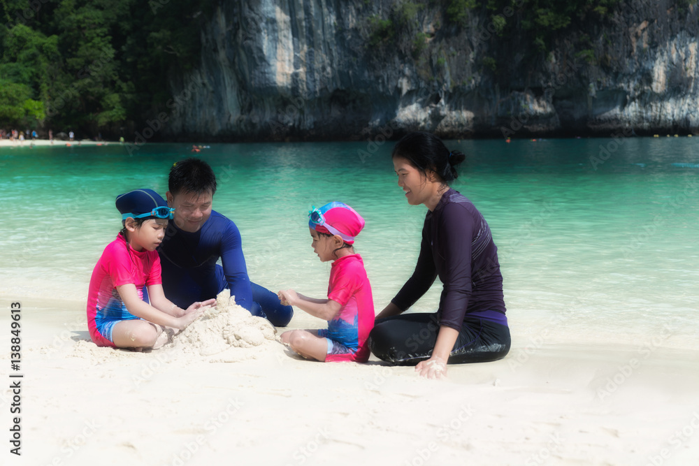 Asian family with father, mother and daughter on beach making sand castles near sea. Summer Travel V