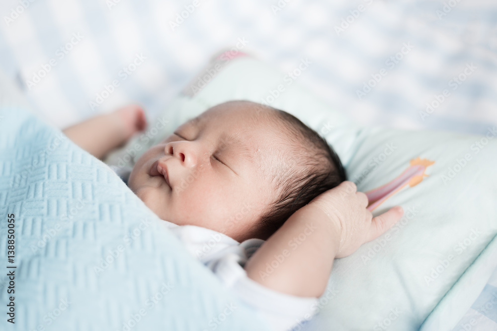 Sleeping Asian baby boy in a blue Blanket at bed. 1 month baby boy.