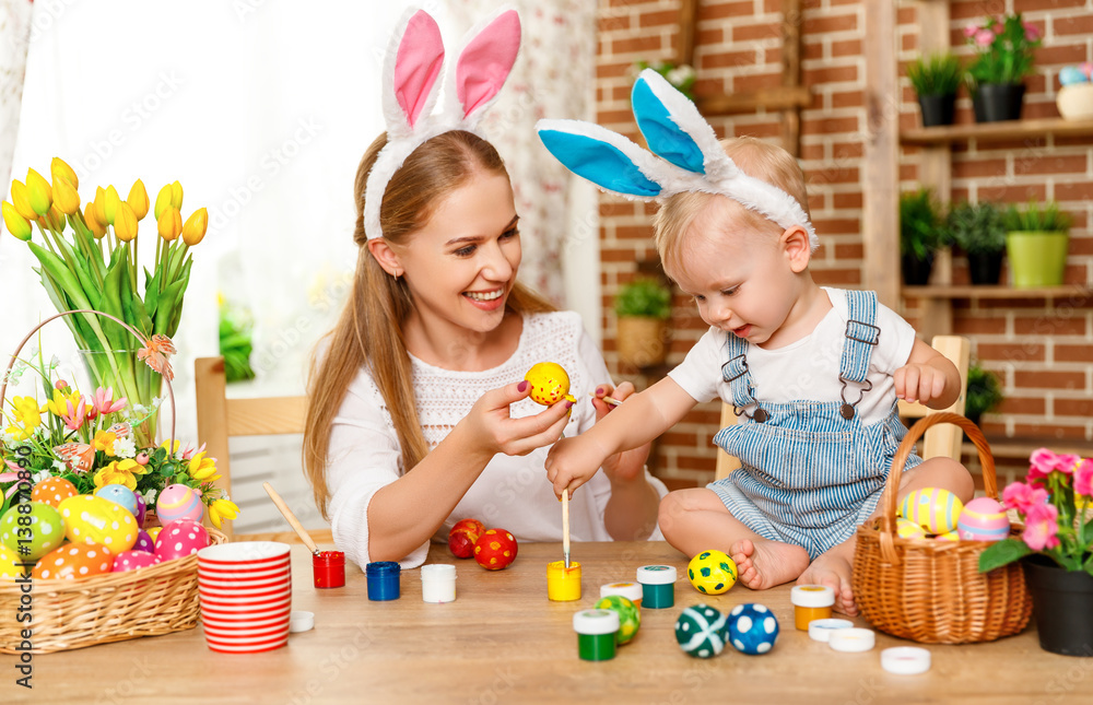 Happy easter! family mother and baby son paint eggs for holiday Easter