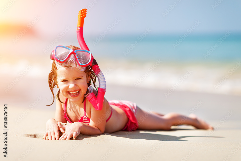 Happy child girl in a mask on the beach