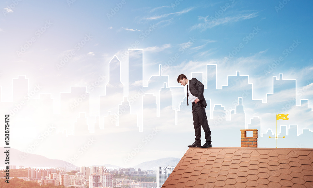 Businessman looking down from roof and modern cityscape at background. Mixed media