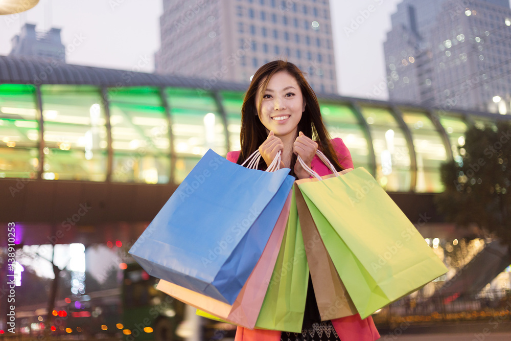 young asian woman with shopping bags on city street