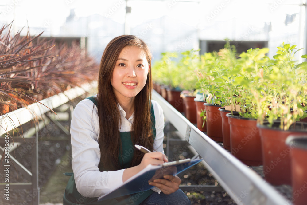 young asian woman works in green house