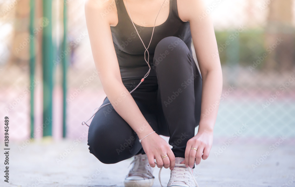 Running shoes. Barefoot running shoes closeup. Female athlete tying laces for jogging on road in min