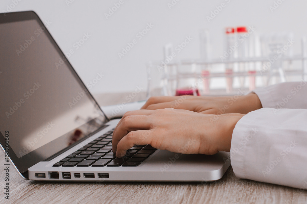 Closeup of medical researcher hands typing on laptop keyboard