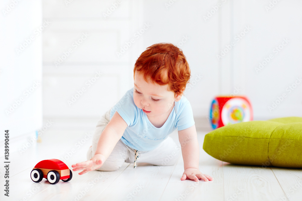 cute infant baby playing with wooden toy car at home