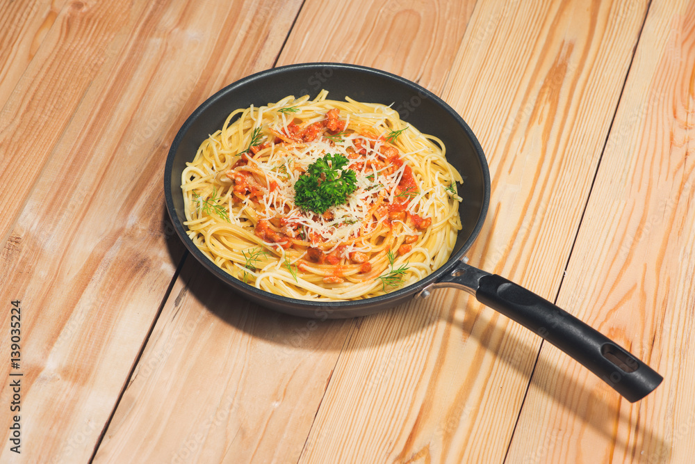 Tasty spaghetti with tomato sauce and meat in pan on wooden table.