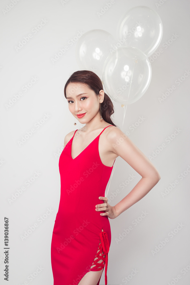 Pretty young asian woman wearing red dress with balloons in hand.