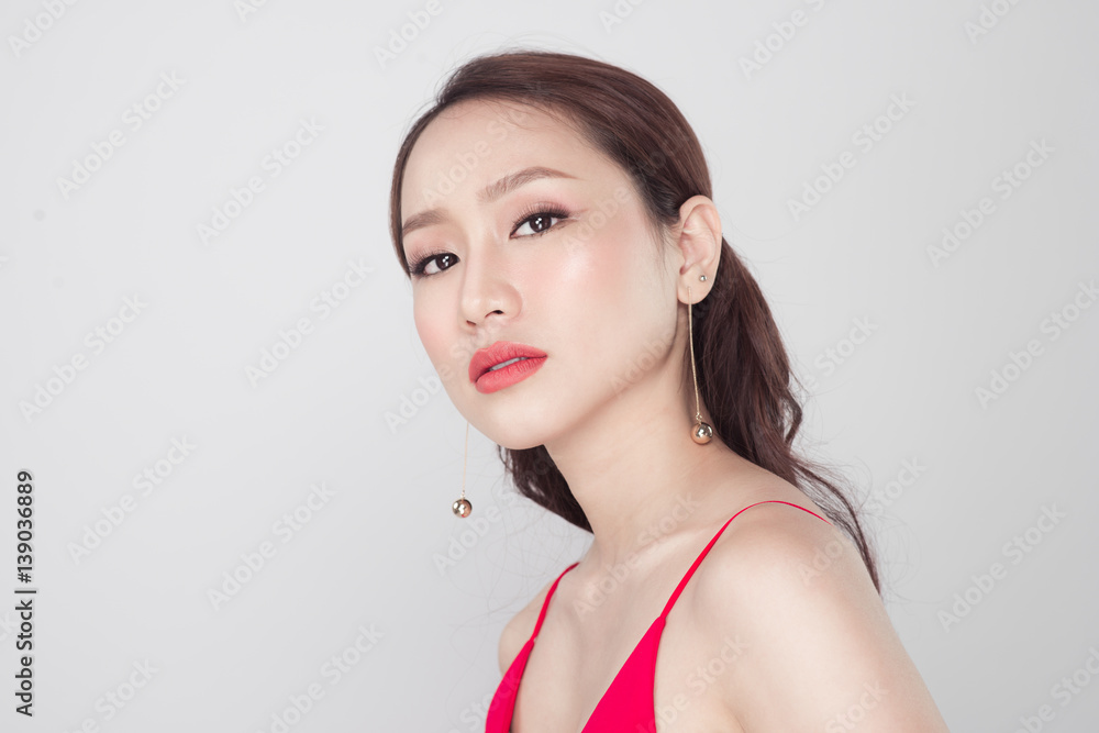 Portrait of stylish asian woman wearing red dress on grey background.