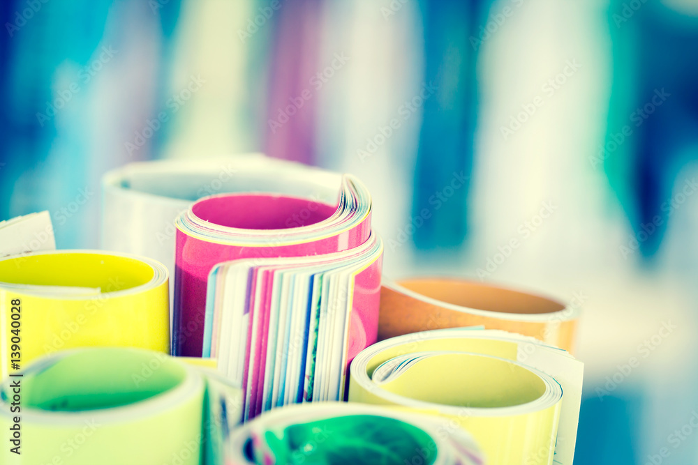 Close up edge of colorful magazine stacking roll with  blurry bookshelf background for bublication a