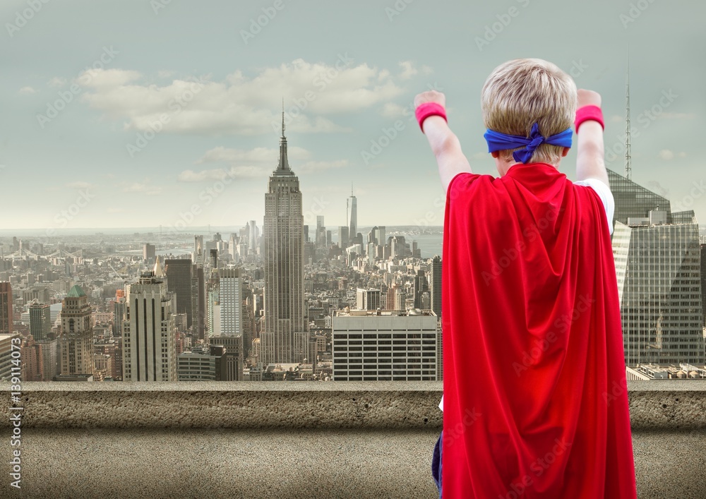 Boy pretending to be a superhero against cityscape in background