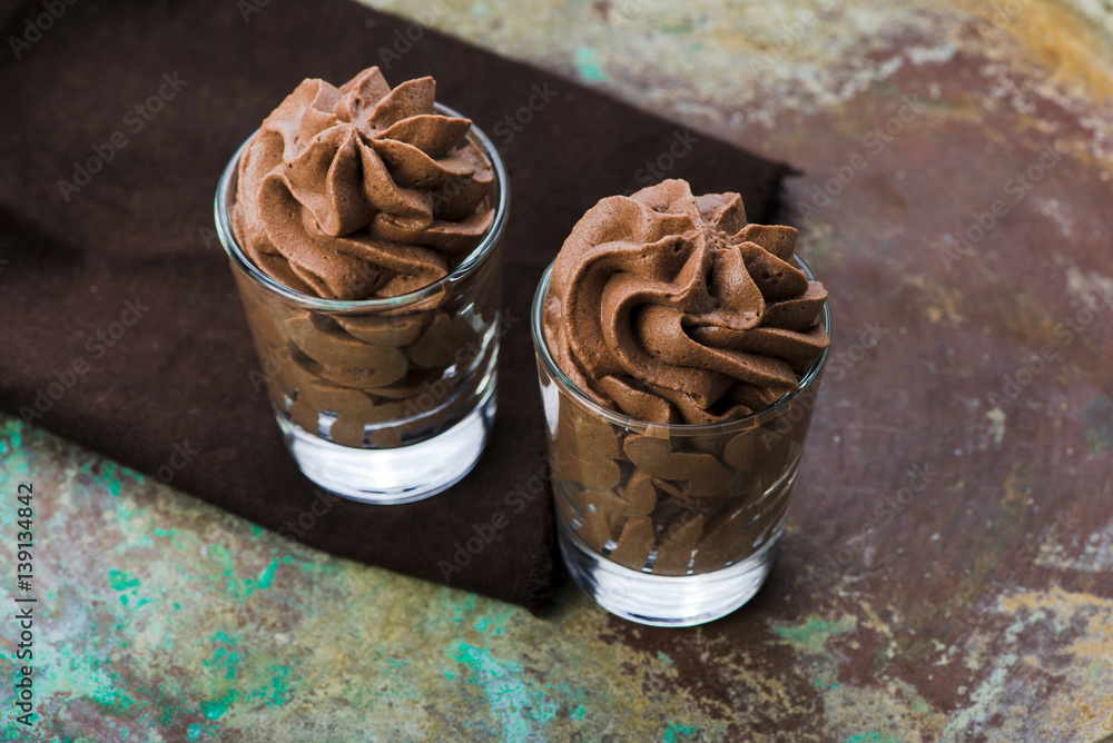 Chocolate mousse with chocolate sauce in a glasses on a vintage background.