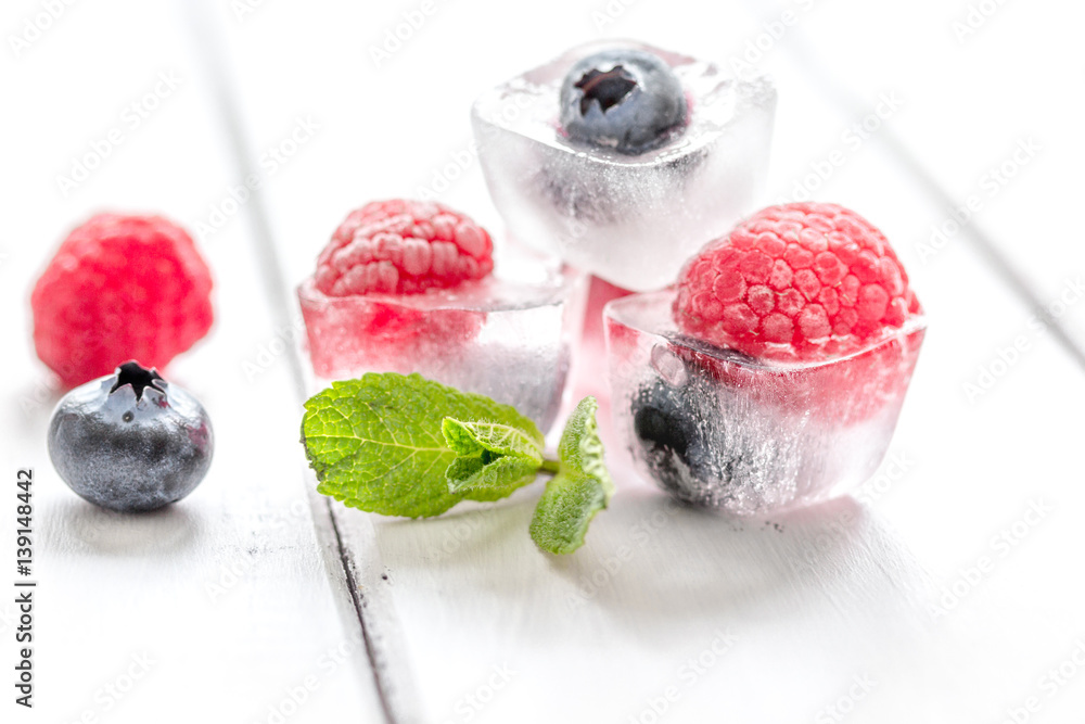 fresh berries with mint in ice cubes on white background