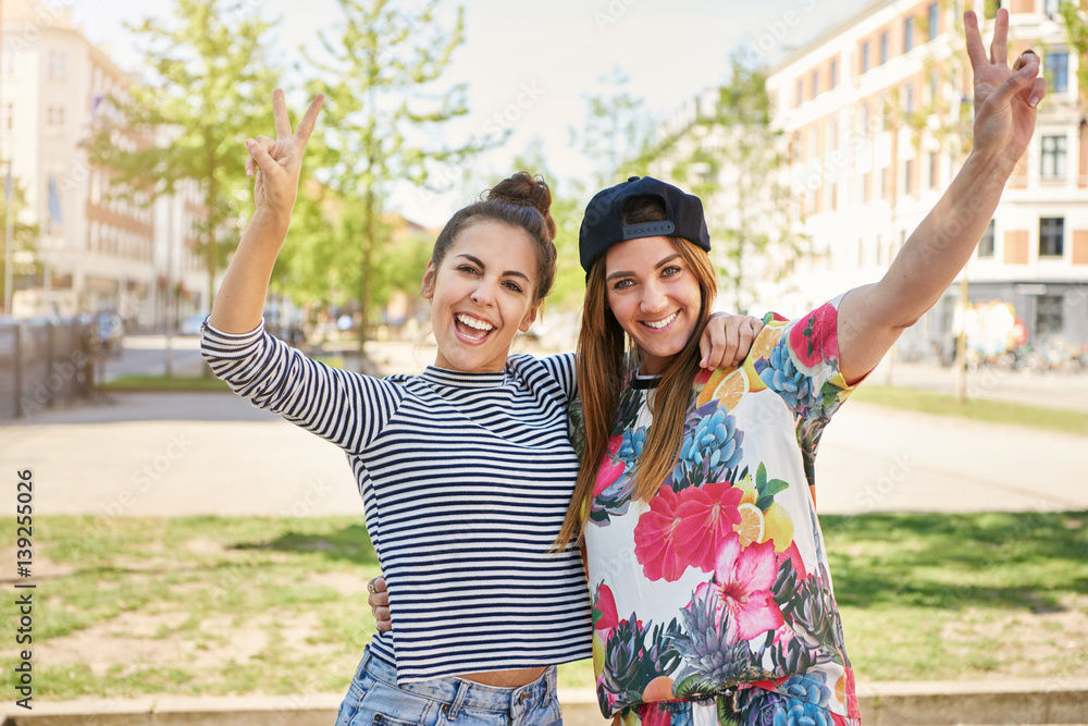 Two happy young students making v-signs