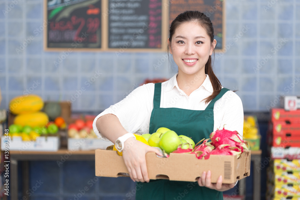 young pretty woman works in fruit store