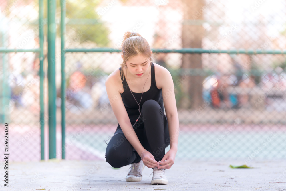 Barefoot running shoes closeup. Female athlete tying laces for jogging on road  Runner getting ready