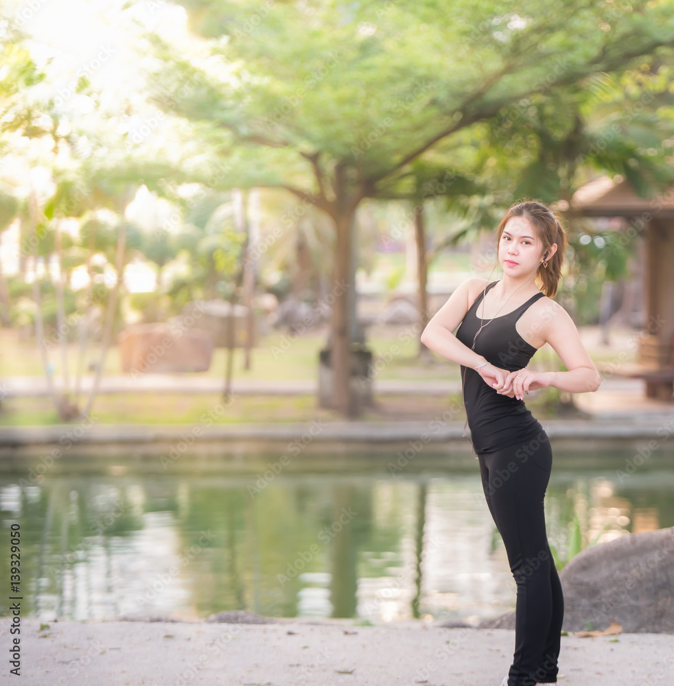 Young female stretching before fitness training session at the park. Healthy young woman warming up 