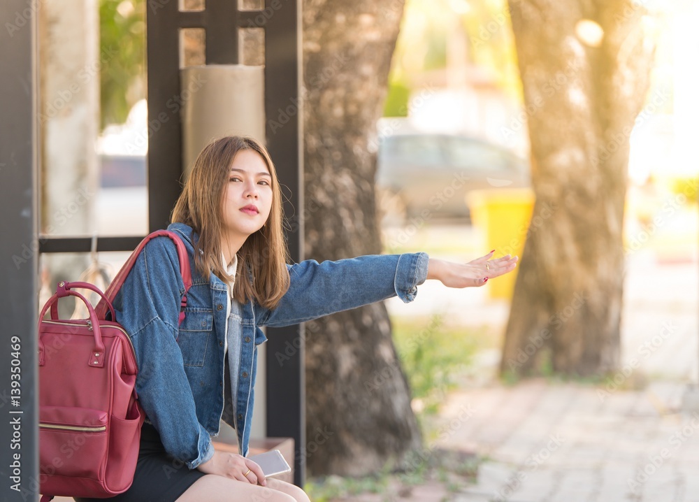 Portrait of a beautiful young Asia woman waiting for a bus or call Something.hitchhiking on the road