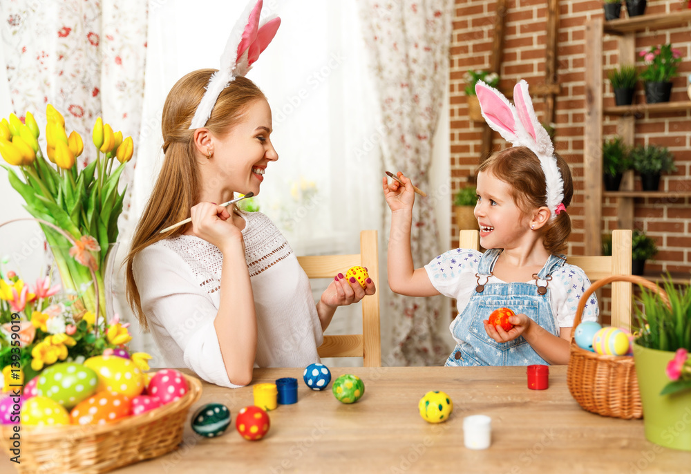 Happy easter! family mother and child daughter paint eggs for holiday Easter