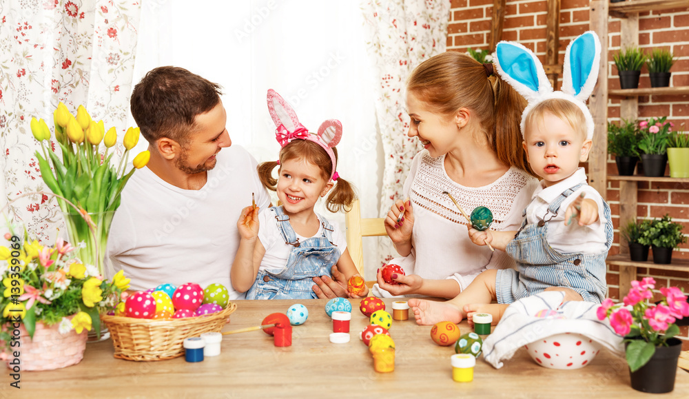 Happy easter! family mother, father and children paint  eggs for holiday.