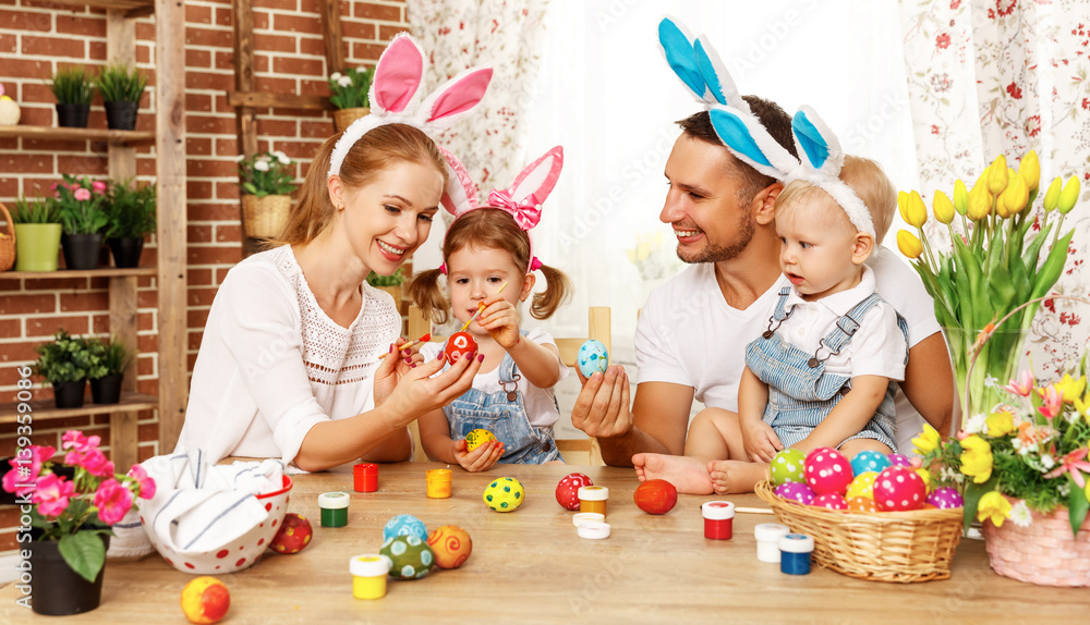 Happy easter! family mother, father and children paint  eggs for holiday.