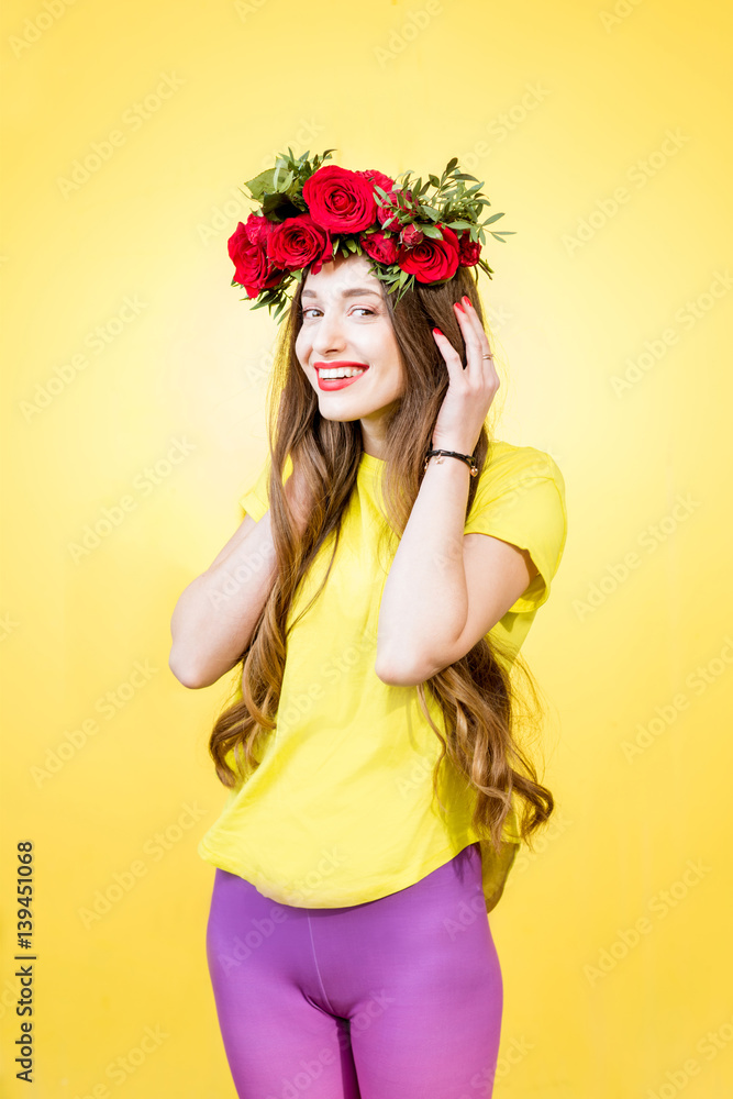 Colorful portrait of a beautiful woman in yellow t-shirt with wreath made of red roses on the yellow