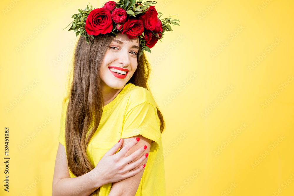 Colorful portrait of a beautiful woman in yellow t-shirt with wreath made of red roses on the yellow