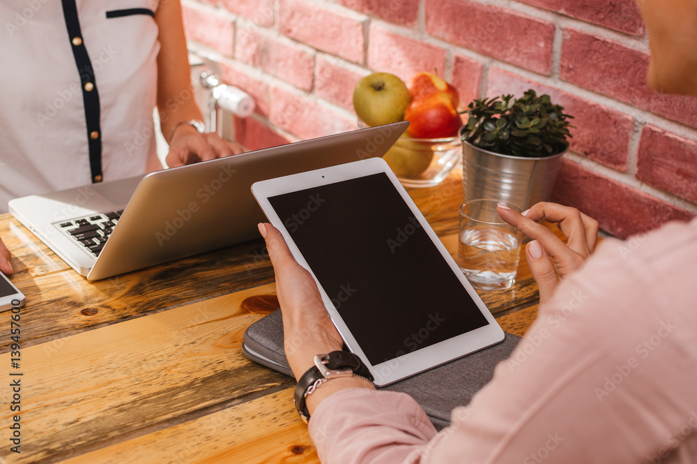 Back view of Young business woman sitting in office at table and using tablet.