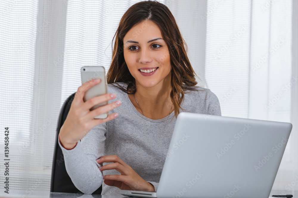 Girl using cellphone while working on computer