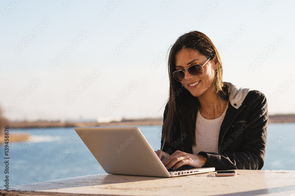 Smiling girl working on laptop outdoor